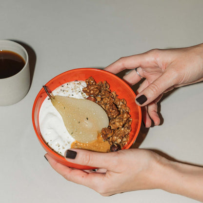 Miso granola bundle in a handcrafted bowl with yogurt and pear, accompanied by a cup of coffee.