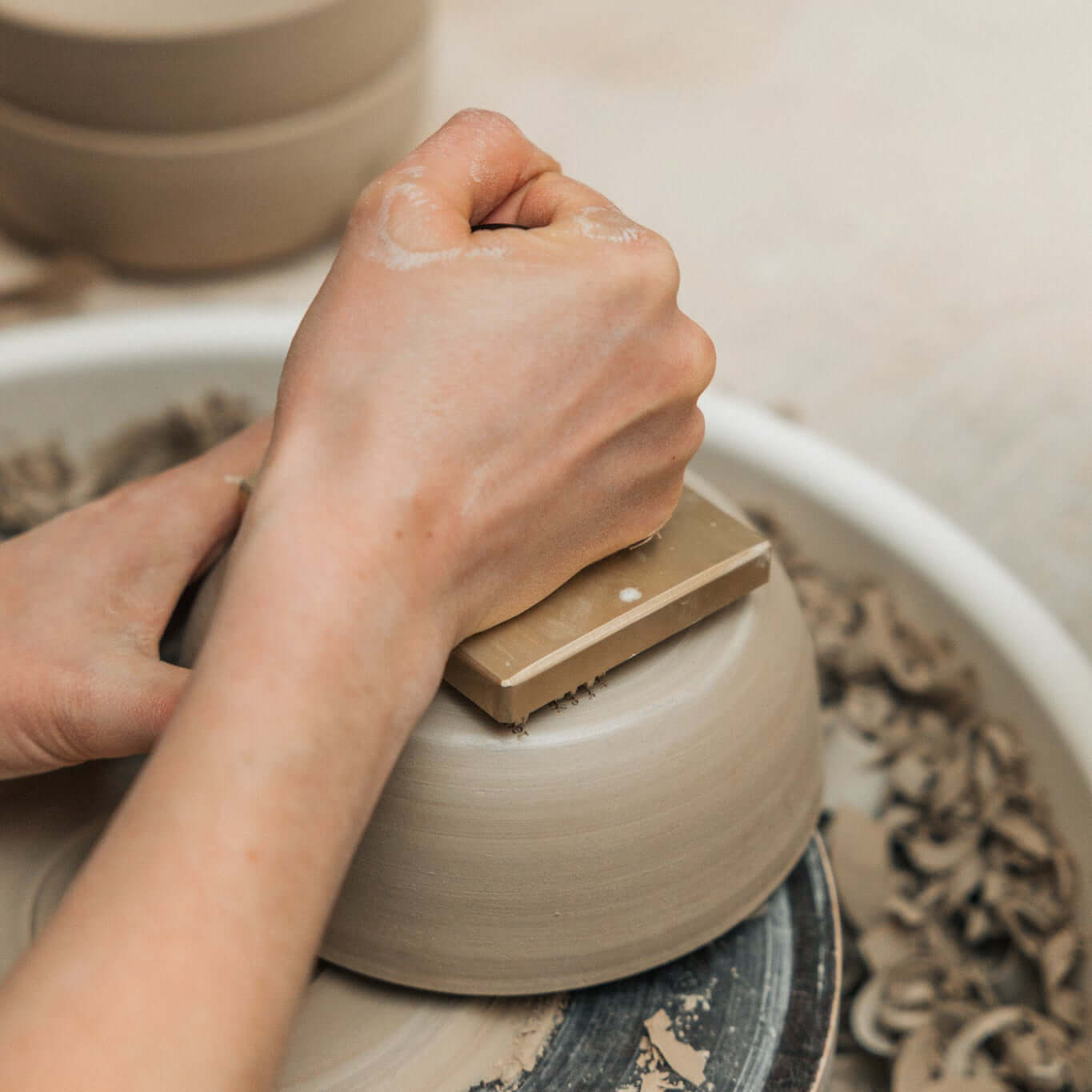 Hände formen eine handgefertigte Müslischale für das Miso Granola Bundle auf einer Töpferscheibe.