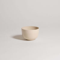 Cream-colored stoneware bowl with a smooth finish, ideal for serving food or decorative use.