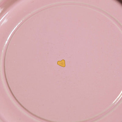 Detail der Handgemachte Keramik Untertasse mit goldenen Herzen auf rosa Hintergrund.