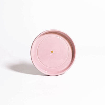 Handgemachte Keramik Untertasse in Rosa mit goldenen Herzdetail auf einem weißen Hintergrund.