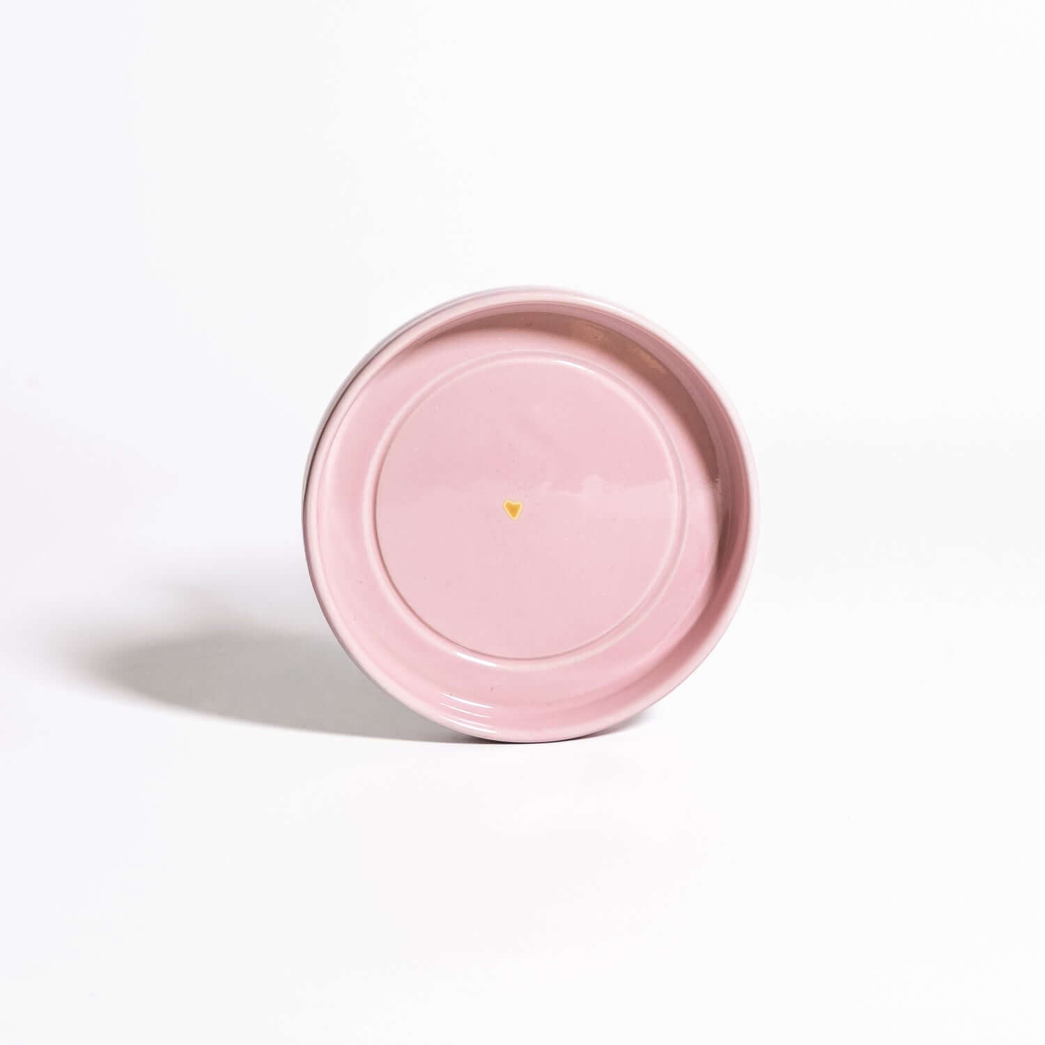 Handgemachte Keramik Untertasse in Rosa mit Golddetail auf weißem Hintergrund.