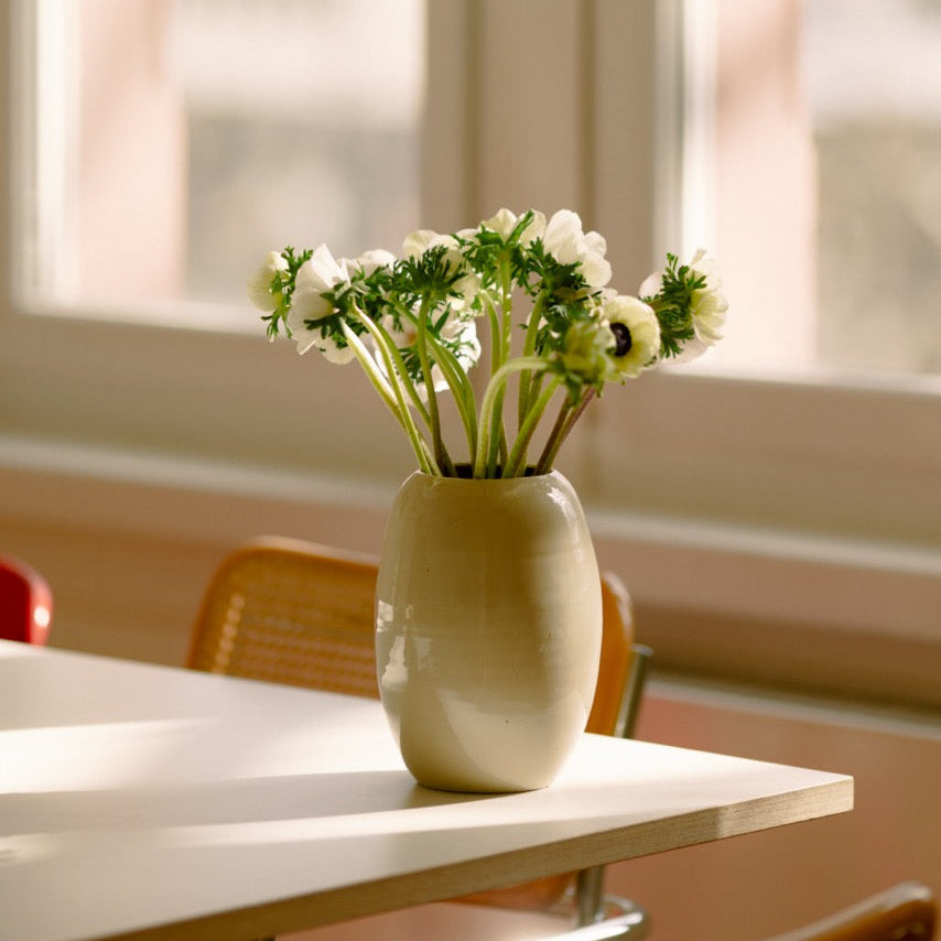 Handgemachte Keramik Blumenvase mit Blumen auf einem Tisch im Sonnenlicht.