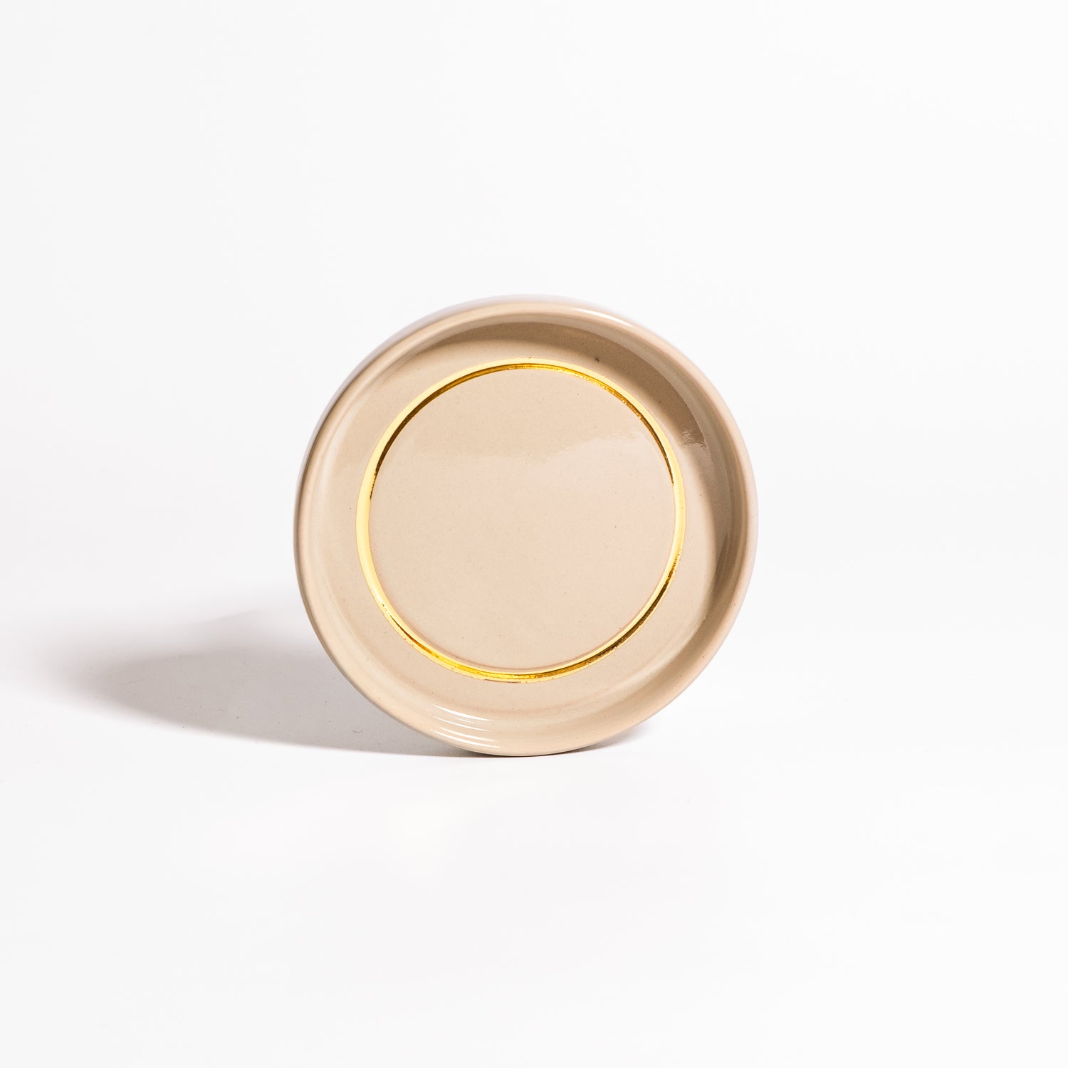 Handgemachte Keramik Untertasse in Salbei mit Golddetail auf weißem Hintergrund.