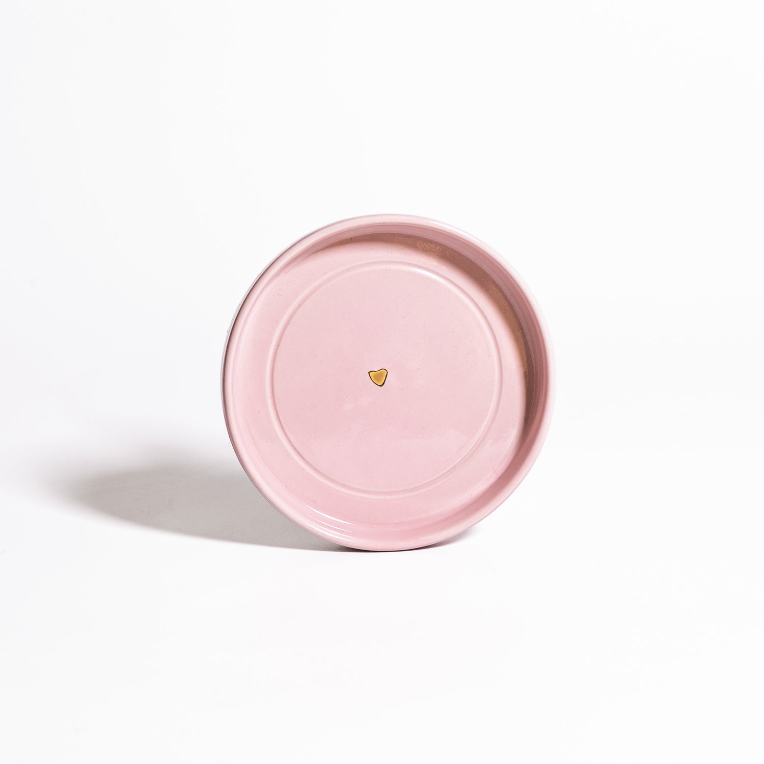 Handgemachte Keramik Untertasse in Rosa mit goldenen Herzdetail auf einem weißen Hintergrund.