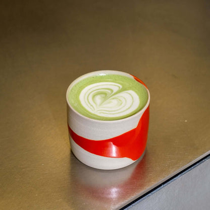 handgemachter Kaffeebecher Splash Rot mit grüner Teetasse und Herzmuster auf der Oberfläche.