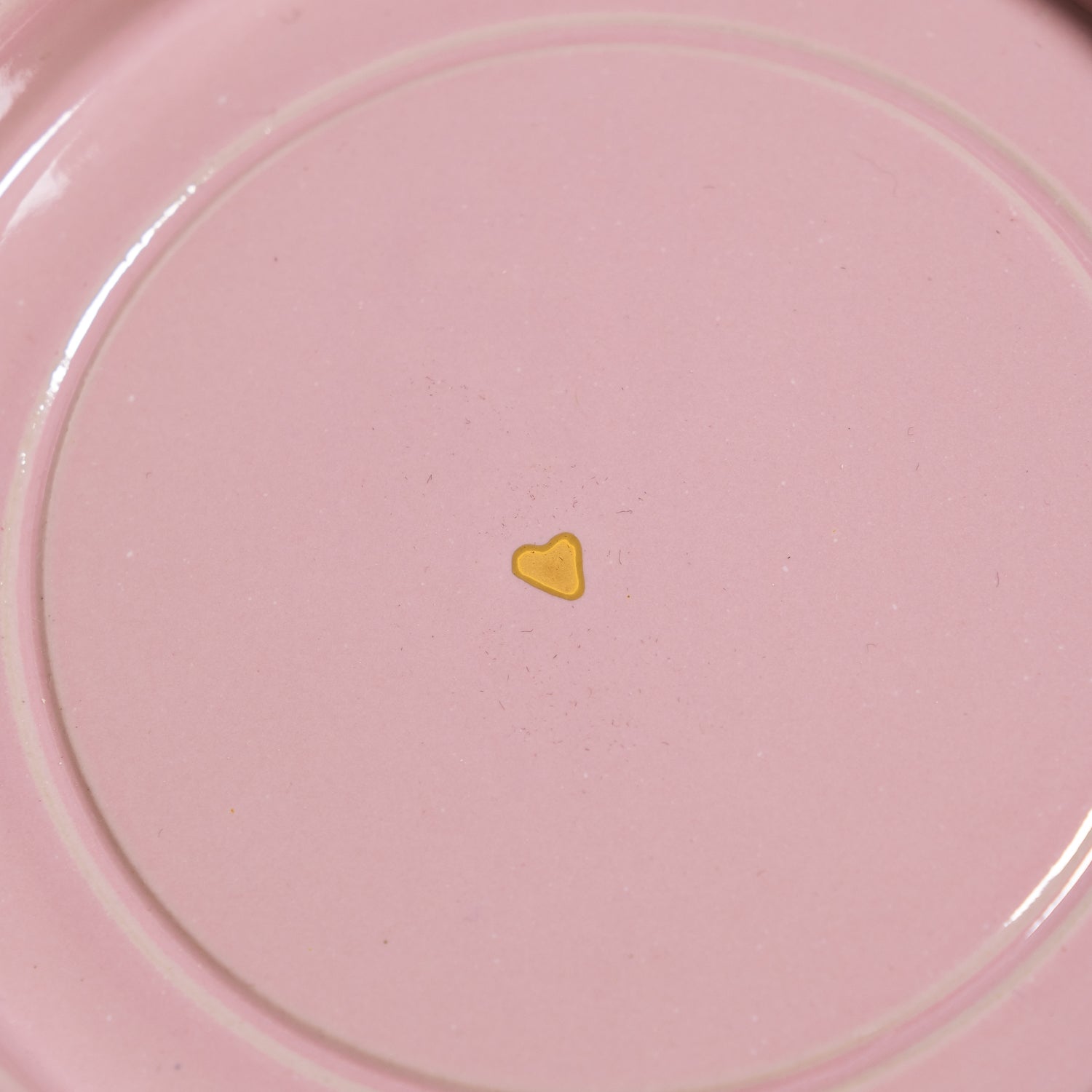 Detail der Handgemachte Keramik Untertasse mit goldenen Herzen auf rosa Hintergrund.