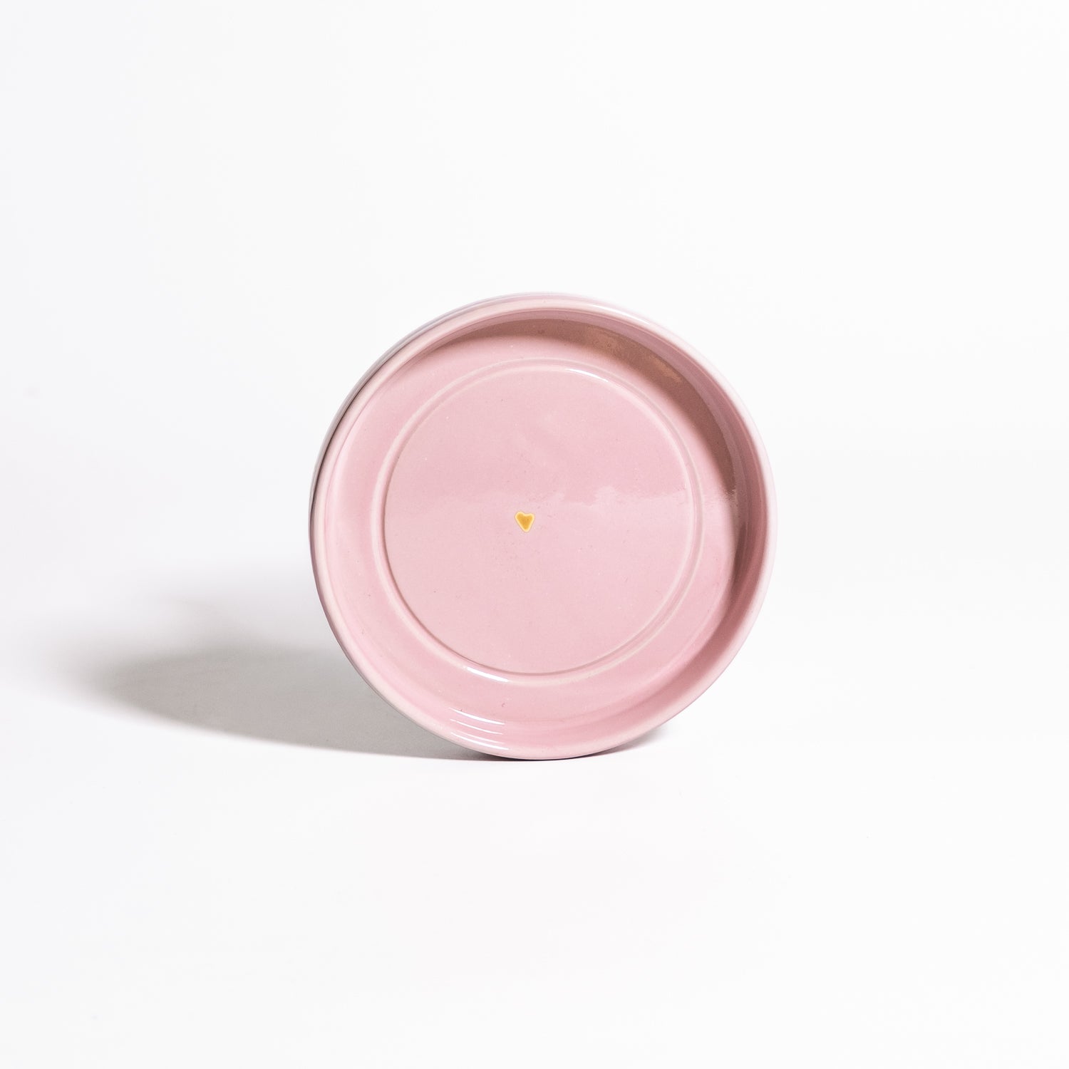 Handgemachte Keramik Untertasse in Rosa mit Golddetail auf weißem Hintergrund.