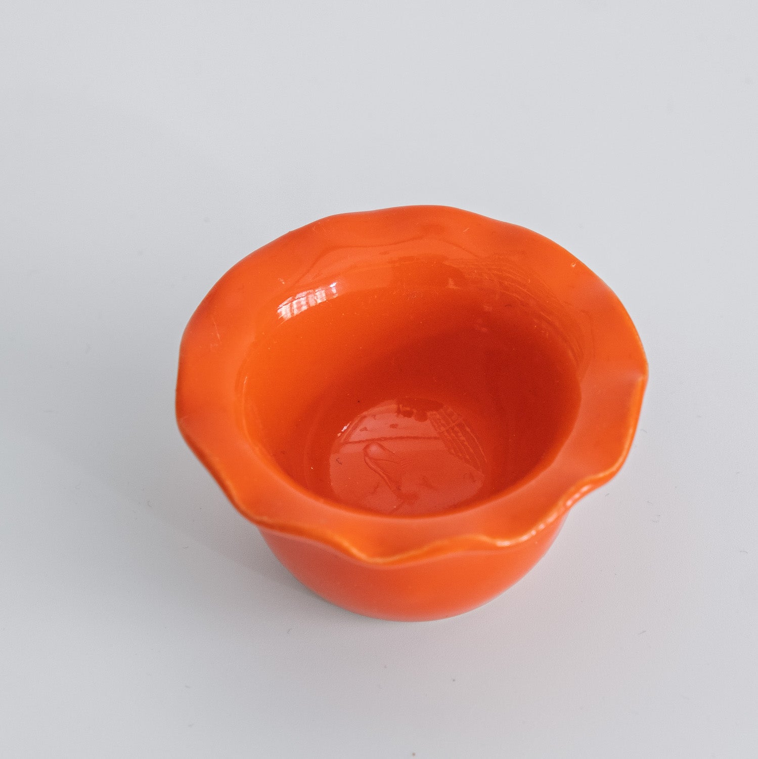 Handgemachter Eierbecher aus Steinzeug in leuchtendem Orange mit welligem Rand.