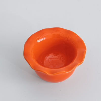 Handgemachter Eierbecher aus Steinzeug in leuchtendem Orange mit welligem Rand.