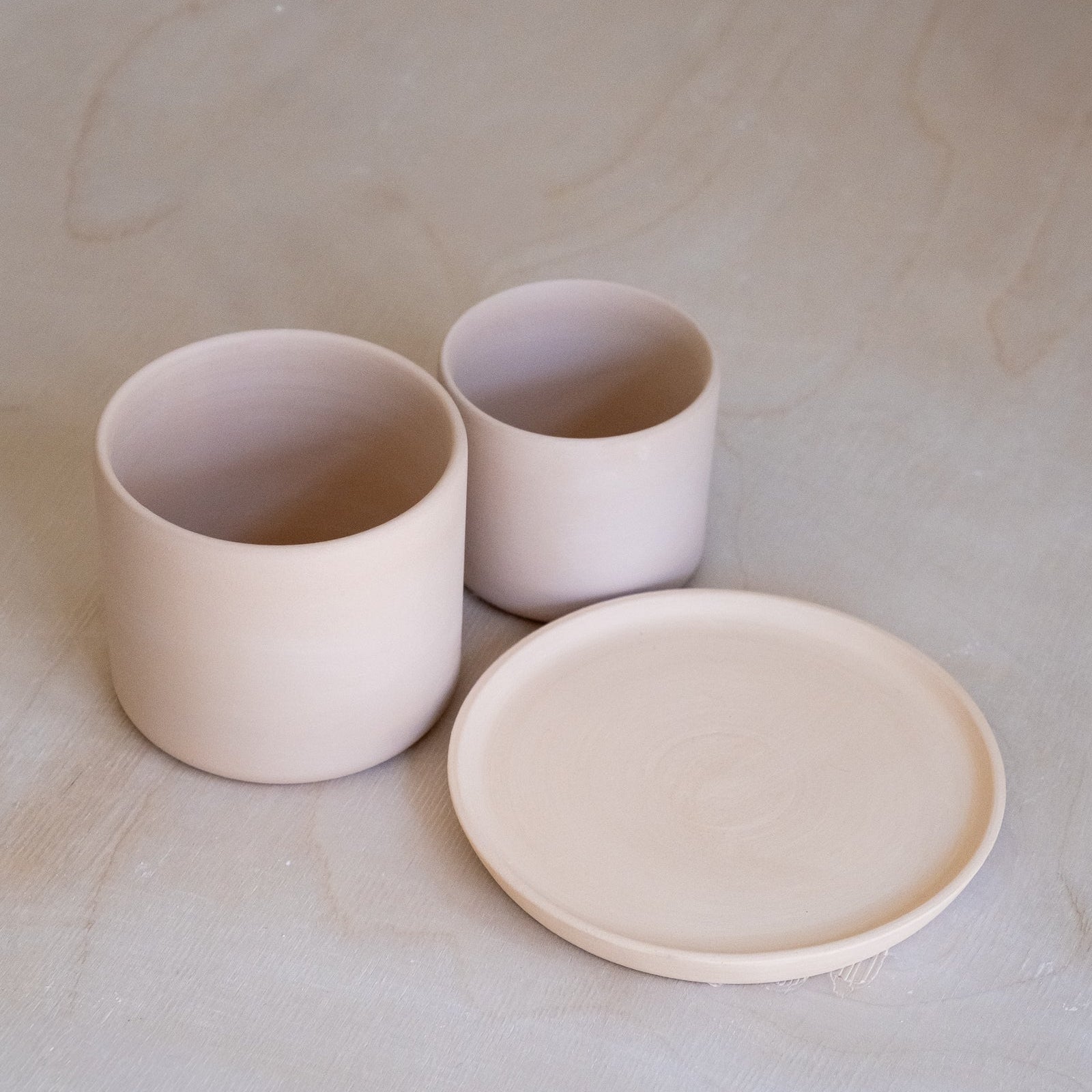 Zwei unglasierten Töpfe und eine Untertasse aus Keramik, perfekt für den Glasur Workshop Frankfurt.