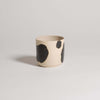 Handcrafted stoneware cup with black brush strokes, showcasing a unique design and glossy finish.