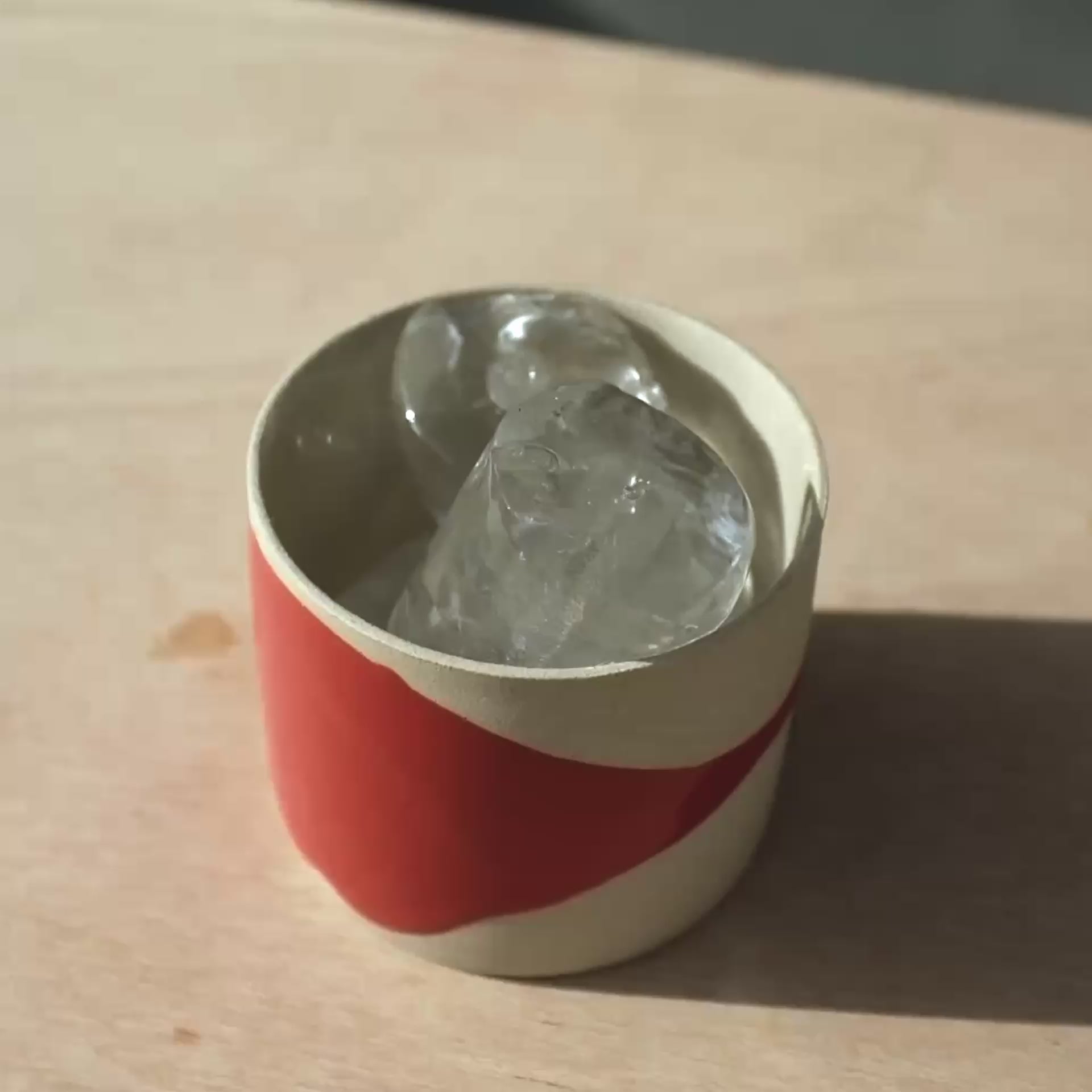 Kaffeetasse - Splash Red mit Kristallen gefüllt auf einem Holztisch.