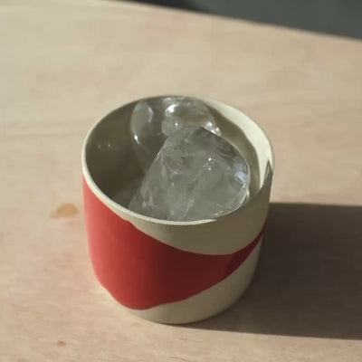 Kaffeetasse - Splash Red mit Kristallen gefüllt auf einem Holztisch.