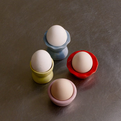 4er Set - handgemachtes Eierbecher Set aus Steinzeug in gemischten Farben mit Eiern.