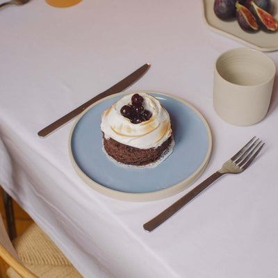 Ein Steinzeug Frühstücksteller in Eisblau mit Schokoladenkuchen und Sahne, hergestellt in Deutschland.
