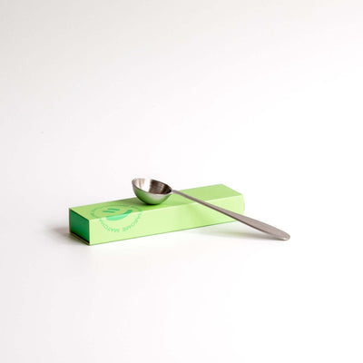 Matcha Löffel aus Edelstahl auf grünem Karton, ideal für präzises Matcha Ritual.