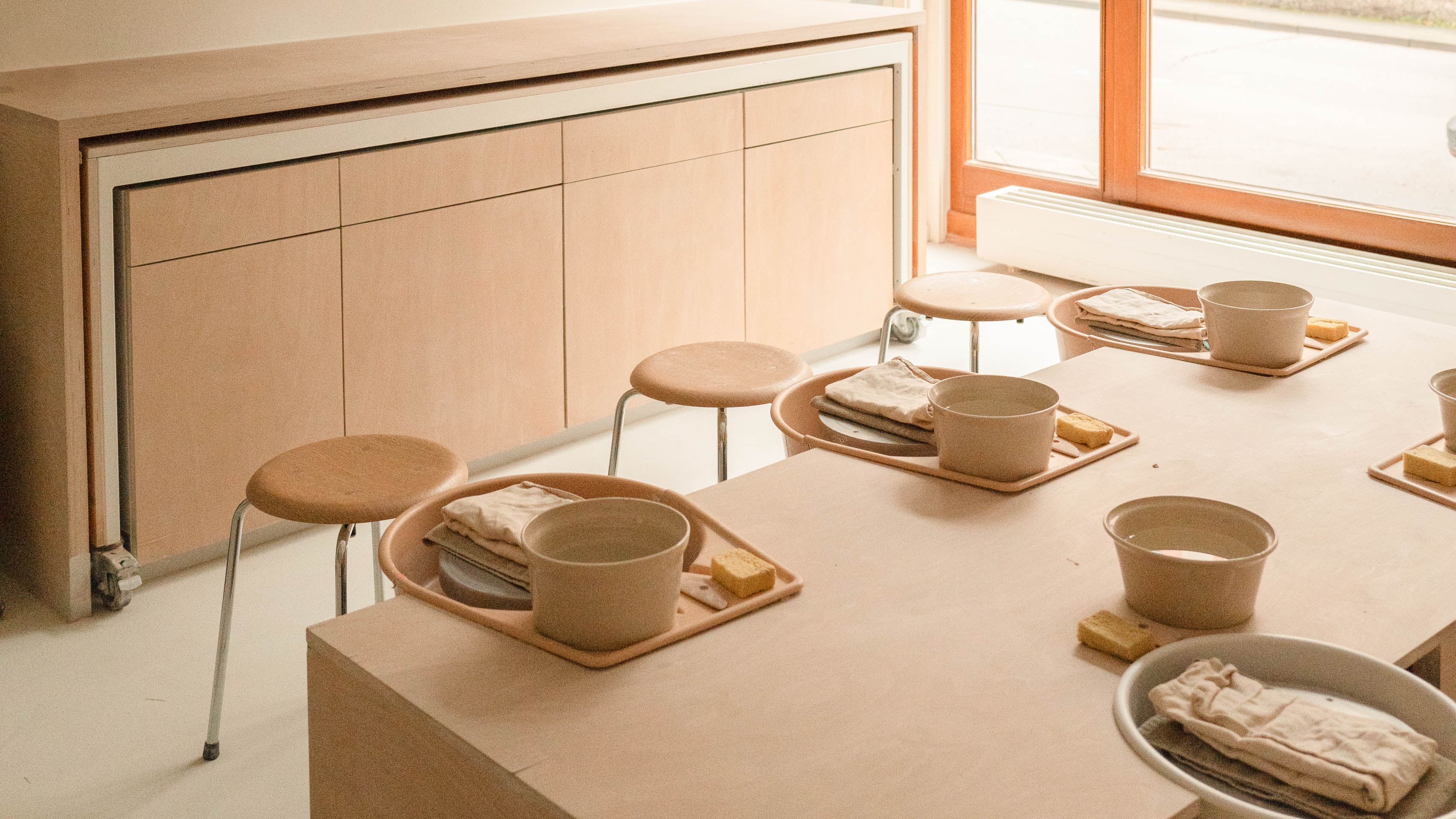 Handgemacht, minimalistischer Essbereich mit Holztisch und einfachen Stühlen, dekoriert mit Tellern und Schüsseln.
