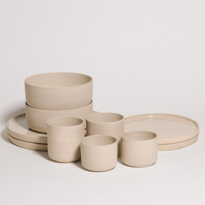 creme geschirr set 10-teilig, bestehend aus Schalen und Tellern in cremiger Farbe, aus grauem Steinzeug gefertigt.