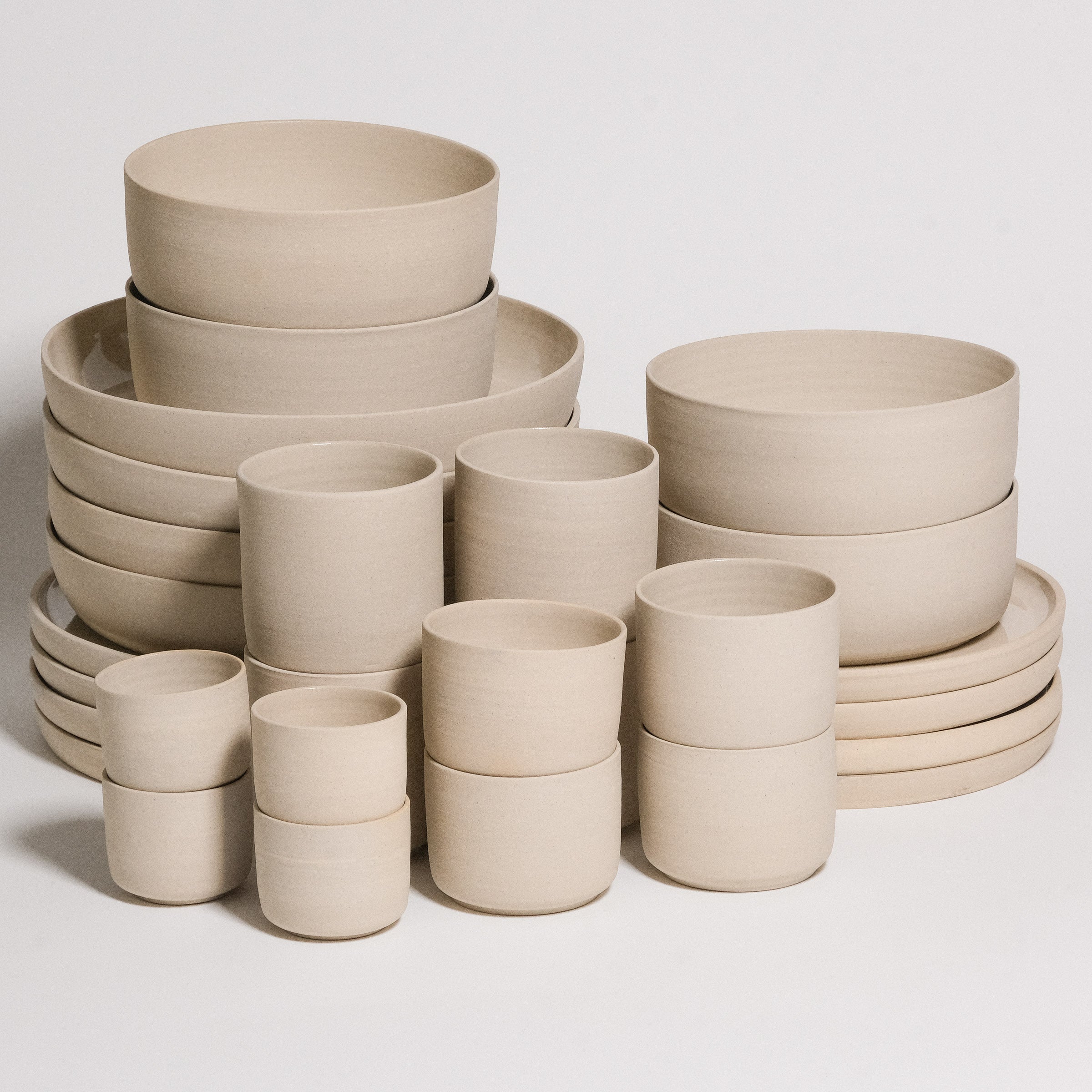 creme geschirr set 28-teilig aus grauem Steinzeugton mit verschiedenen Tassen und Schalen.